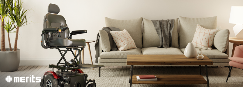 Black power wheelchair with red detailing in living room with couch, table, and plant